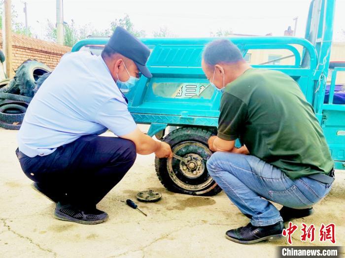 賽旦與民警共同維修三輪摩托車。　依力哈木江 攝