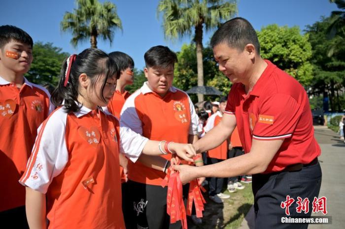 資料圖：廣西華僑實(shí)驗(yàn)高中的教師為高三學(xué)子系上紅絲帶，盼望學(xué)子高考必勝。 俞靖 攝